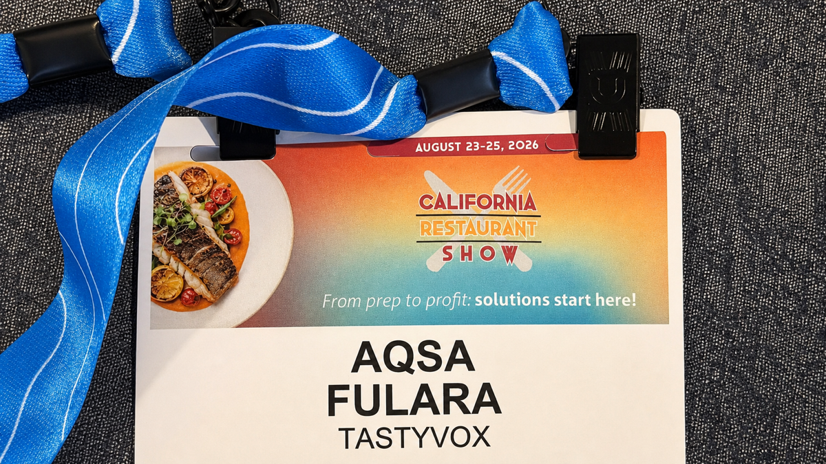 Close-up of Aqsa Fulara's TastyVox badge and blue lanyard from the 2026 California Restaurant Show